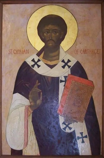 An icon of St. Cyprian holding a Gospel book and making the sign of the Cross with his hand.
